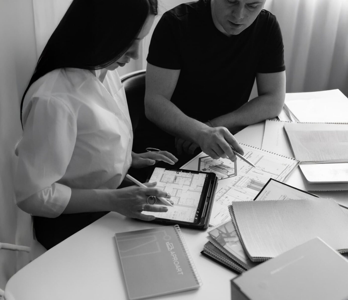 Two people at a desk reviewing blueprints